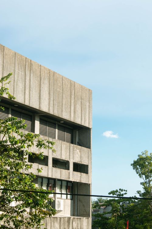 Free A concrete building facade with greenery and blue sky, blending urban and natural elements. Stock Photo