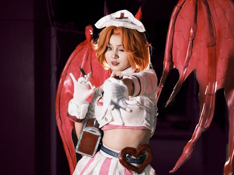 Cosplayer in a demon-themed costume with red wings, posing dramatically. Perfect for fantasy and cosplay themes.