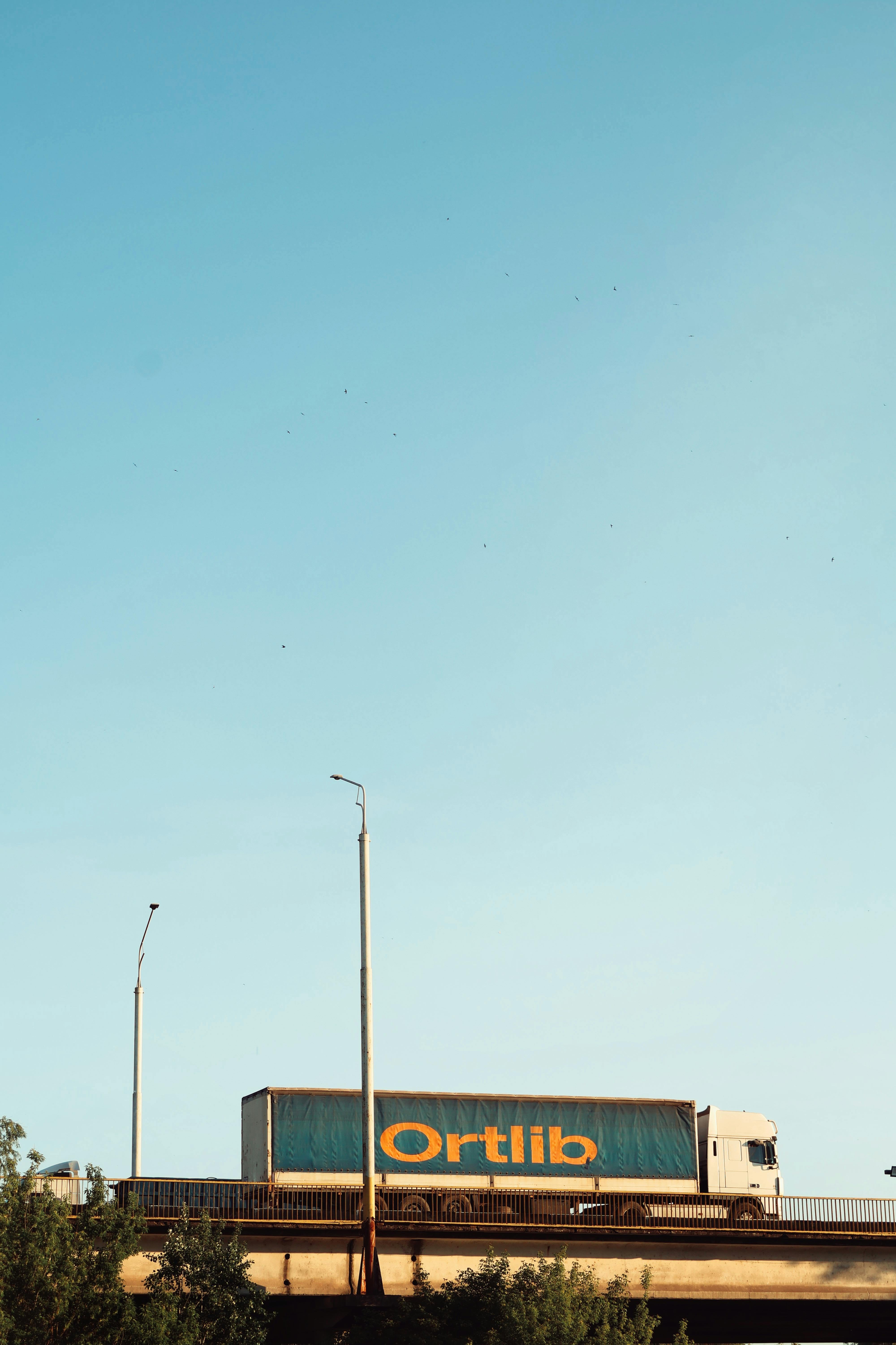 Free A large truck crosses a bridge under a clear blue sky, suggesting transportation or logistics. Stock Photo