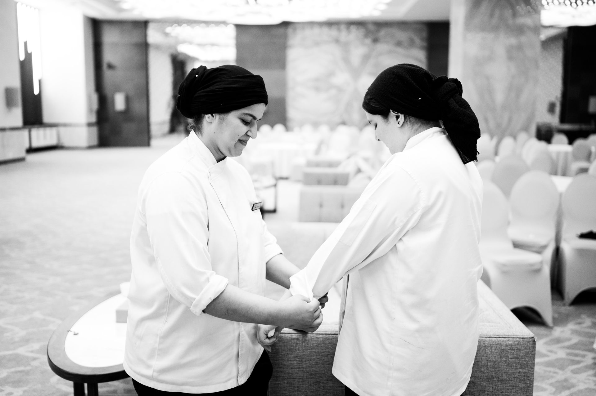 Two chefs in discussion in an elegant Islamabad hotel event space, focusing on teamwork.