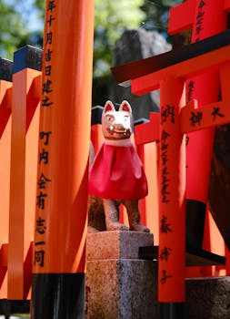 Colorful fox statue among torii gates at Fushimi Inari Shrine, Kyoto.