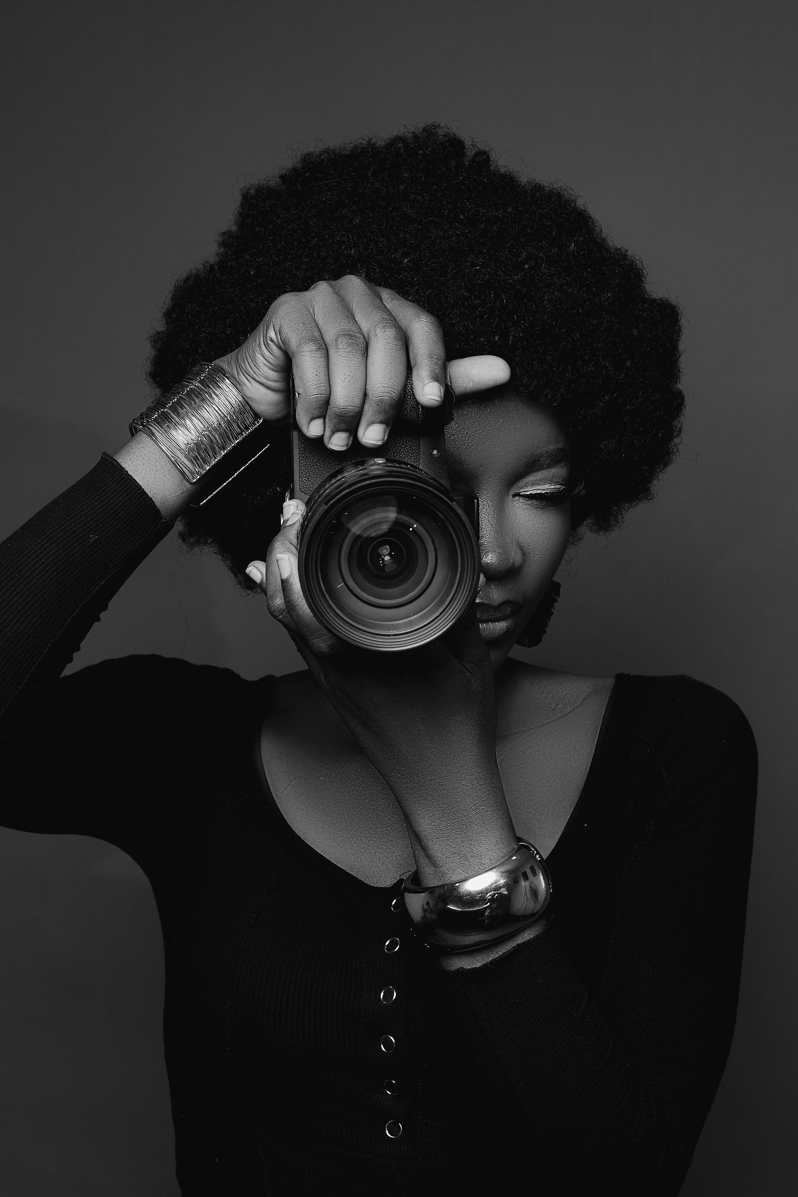 Artistic black and white portrait of a female photographer holding a camera.