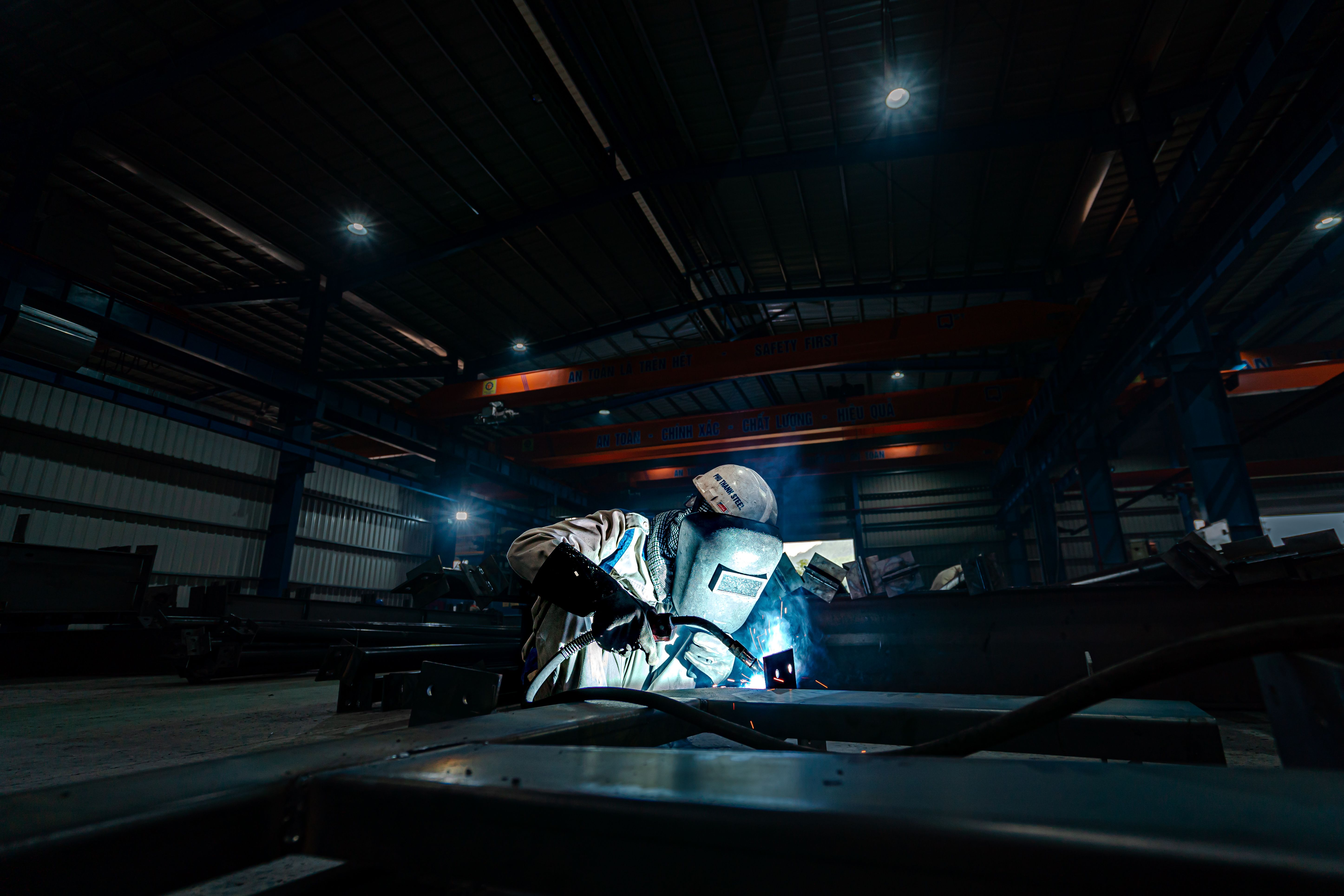 Industrial welder fabricating steel inside a production warehouse