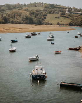 A serene view of boats floating on the calm river in Cantabria, Spain, under a clear sky.