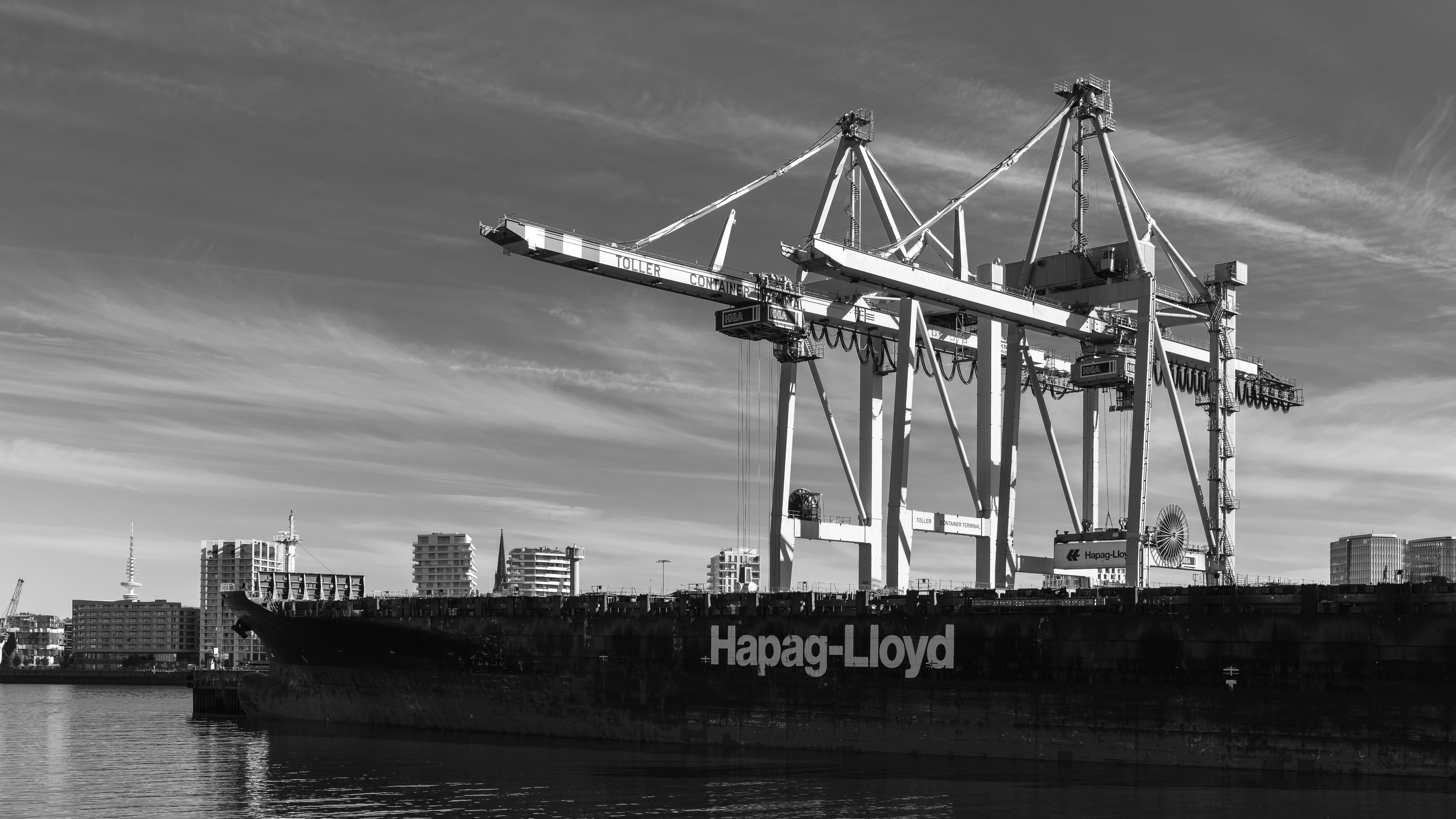 Black and white image of cranes and a container ship at Hamburg port.