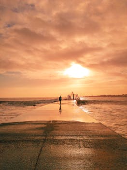 日落时分，一个人走在埃斯托里尔码头上的宁静场景令人惊叹，捕捉到了海滨的宁静氛围