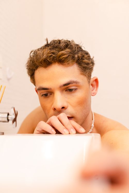 Free Portrait of a man in a bathtub with a contemplative expression, indoors. Stock Photo