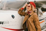 一位戴着太阳镜和红色贝雷帽的时尚女子在户外飞机旁摆姿势