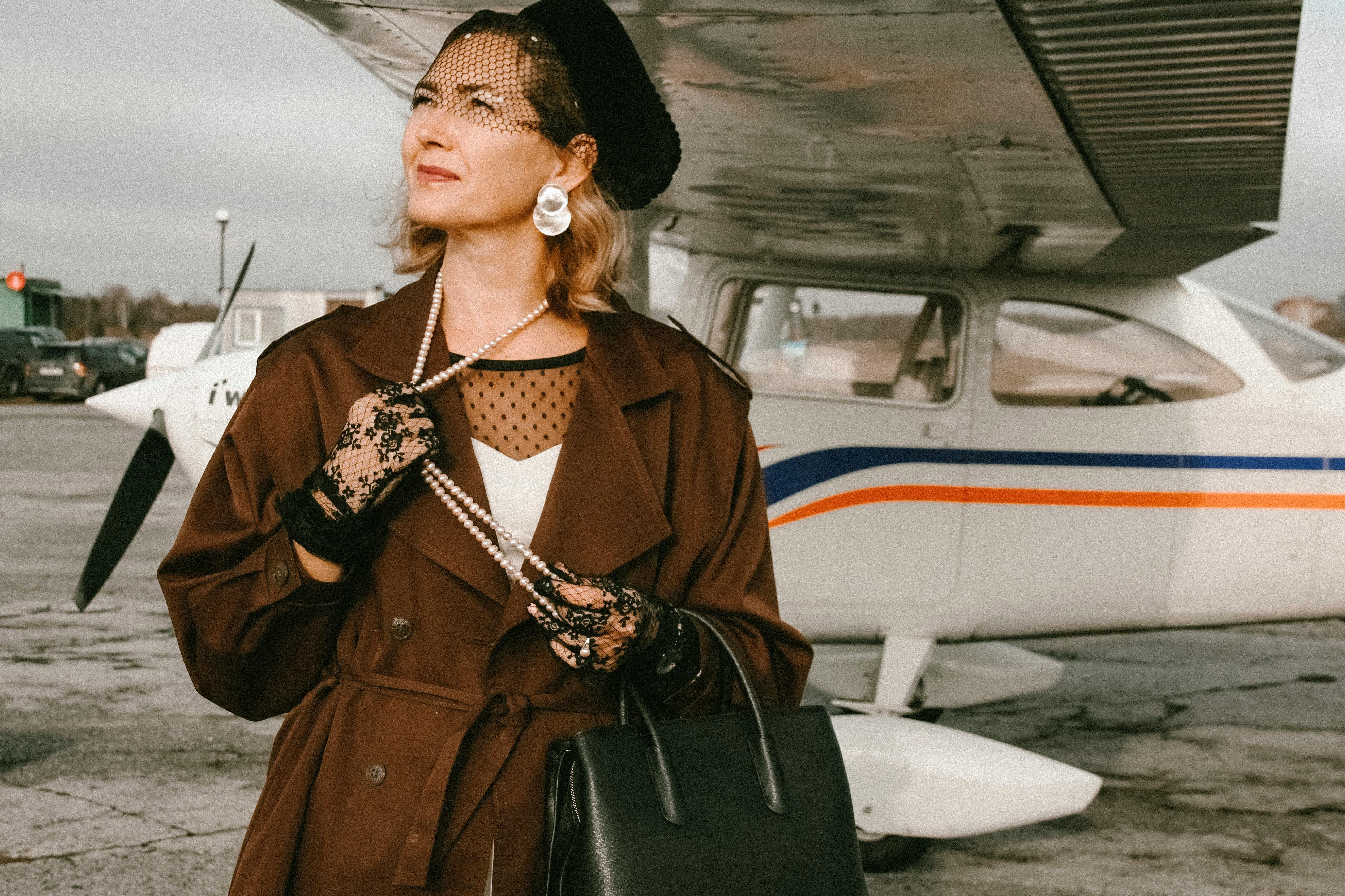 一位优雅的复古风格女子站在机场跑道旁的私人飞机附近