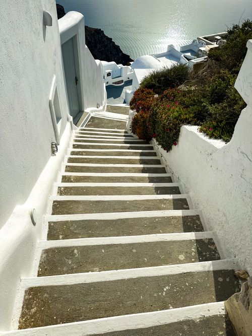 Free Picturesque white steps with blooming flowers leading to a tranquil sea view in Santorini, Greece. Stock Photo