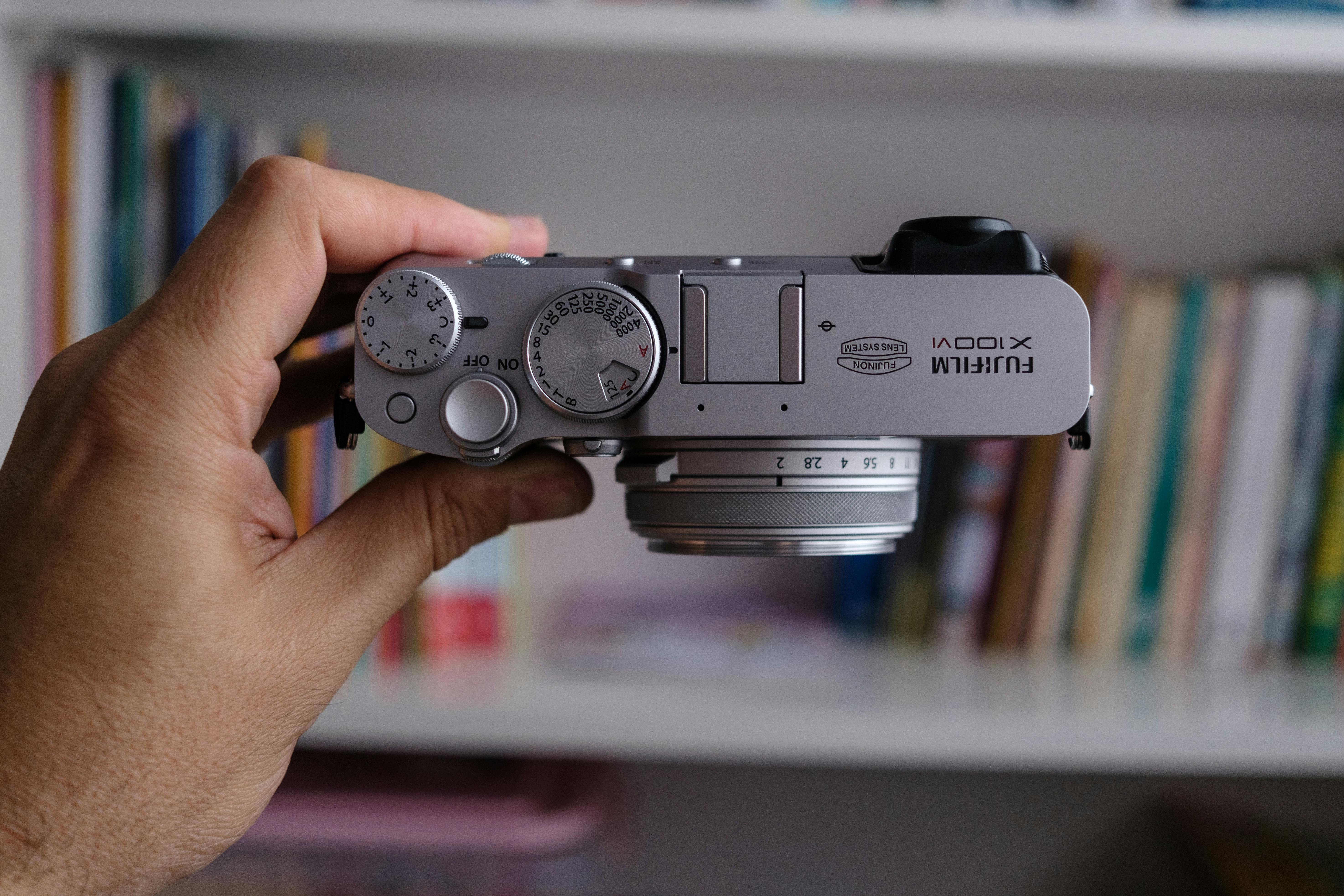 Free Close-up of a silver retro-style digital camera held in hand. Stock Photo
