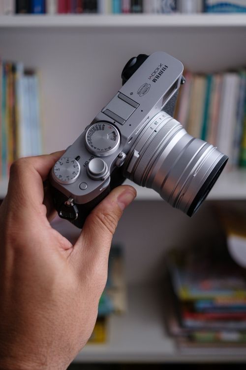 Free Detailed view of a vintage-style silver camera held by hand indoors. Stock Photo