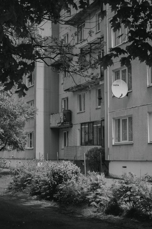 Free Black and white photo of an urban apartment building with trees and satellite dish. Stock Photo