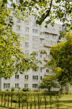 High-rise apartment building surrounded by lush greenery in a serene urban park setting.