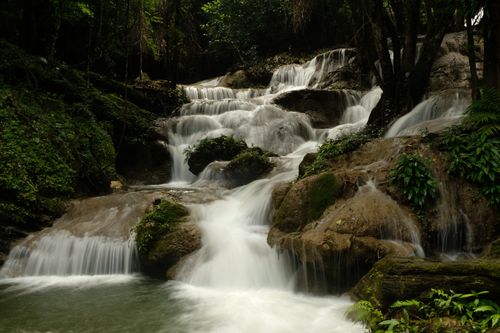 Free Beautiful waterfall cascading over rocks in a lush green forest in Kanchanaburi, Thailand. Stock Photo