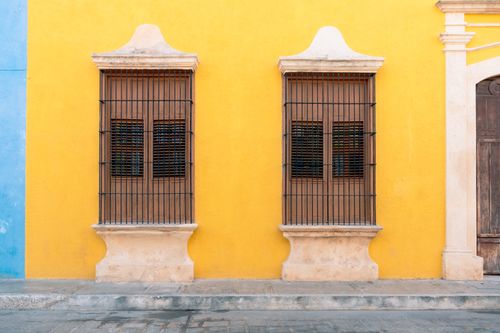 Free Vibrant colonial-style yellow facade with ornate windows in Campeche, Mexico. Stock Photo