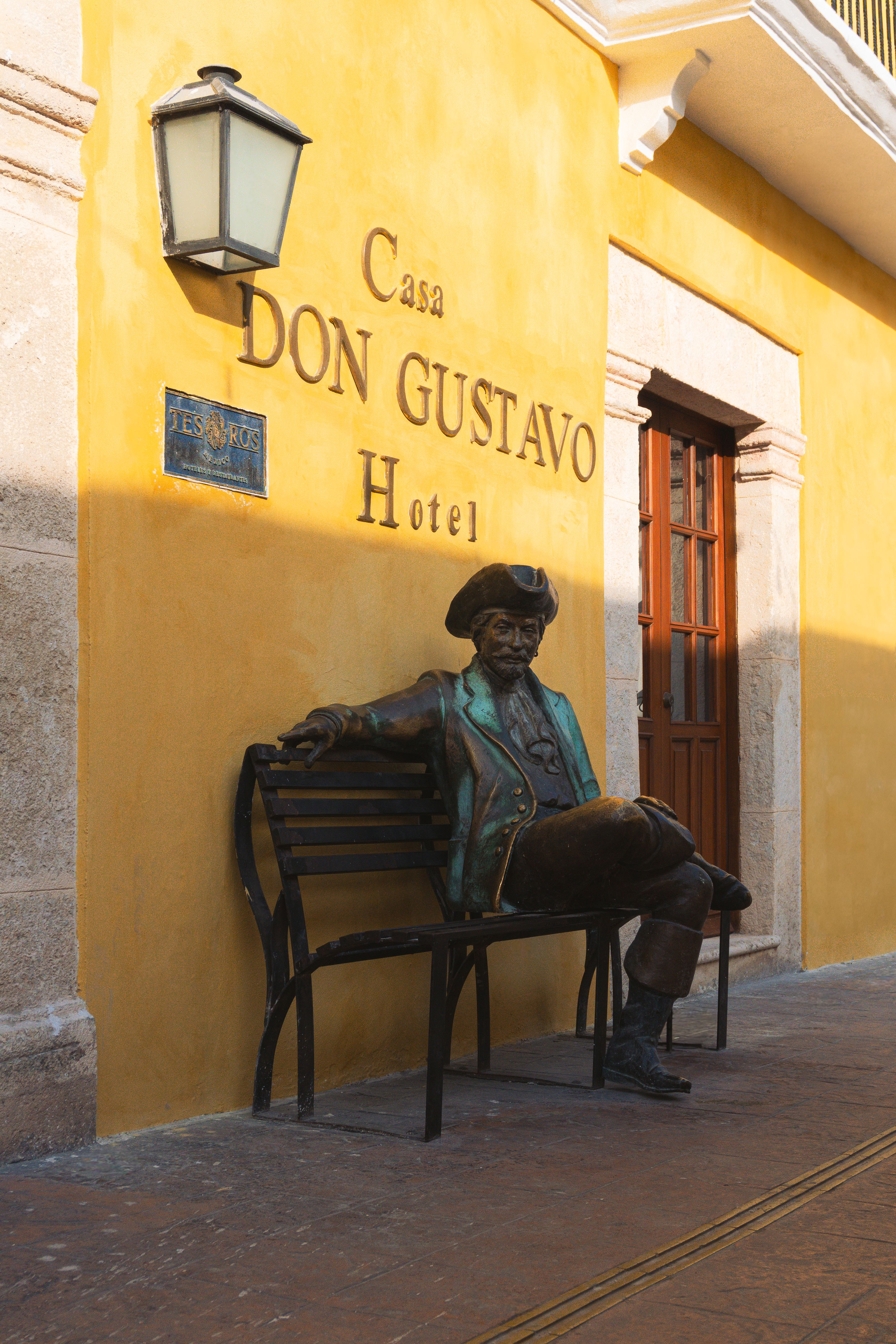 Colonial architecture of Casa Don Gustavo Hotel with bronze statue in Campeche, Mexico.