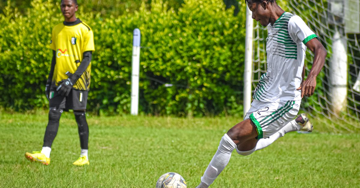 Students in sports uniforms practicing football on a well-maintained field in Ho, Ghana