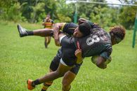Rugby players in an action-packed tackle during a competitive outdoor match on a sunny day.