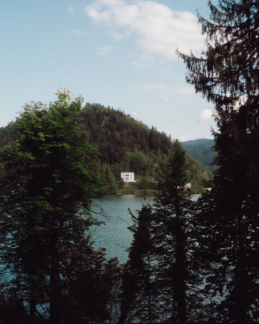 Tranquil mountain lake surrounded by lush forests under a clear sky.
