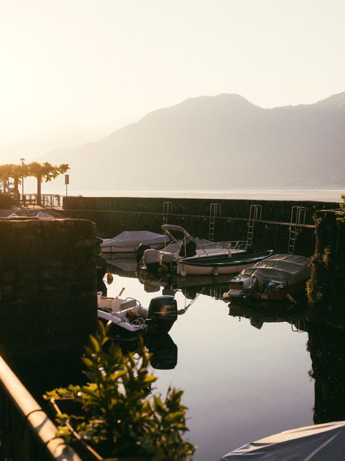 Free Serene view of boats docked by a lake at sunrise with mountains in the background. Stock Photo