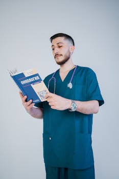 A young male doctor in scrubs reads an oncology book, symbolizing medical education.