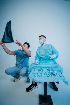 Two doctors in scrubs reviewing an X-ray in a clinical environment with surgical tools.