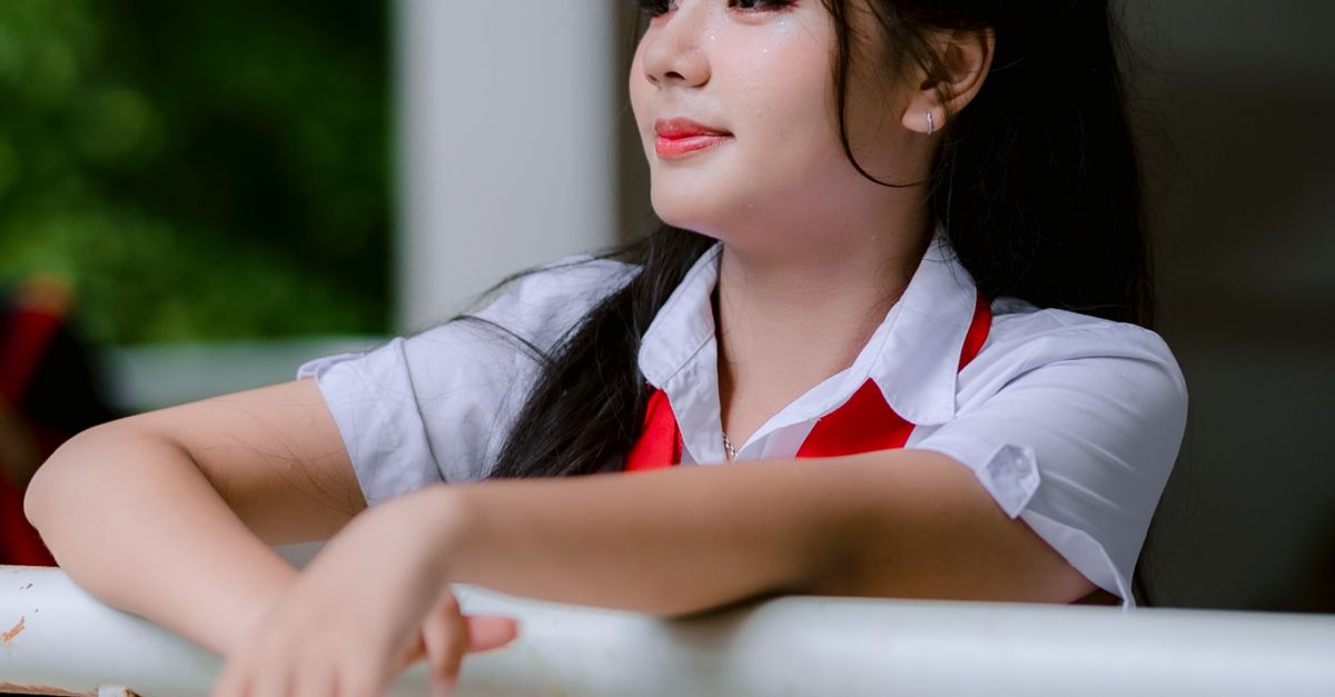 Young Woman in Uniform Leaning on Railing · Free Stock Photo