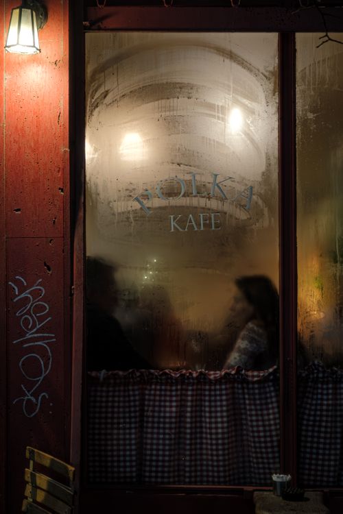 Free Silhouetted figures behind a foggy cafe window with warm interior lighting and a vintage ambiance. Stock Photo