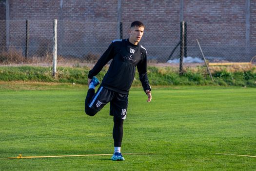 A football player stretching outdoors on the field during training for improved performance.