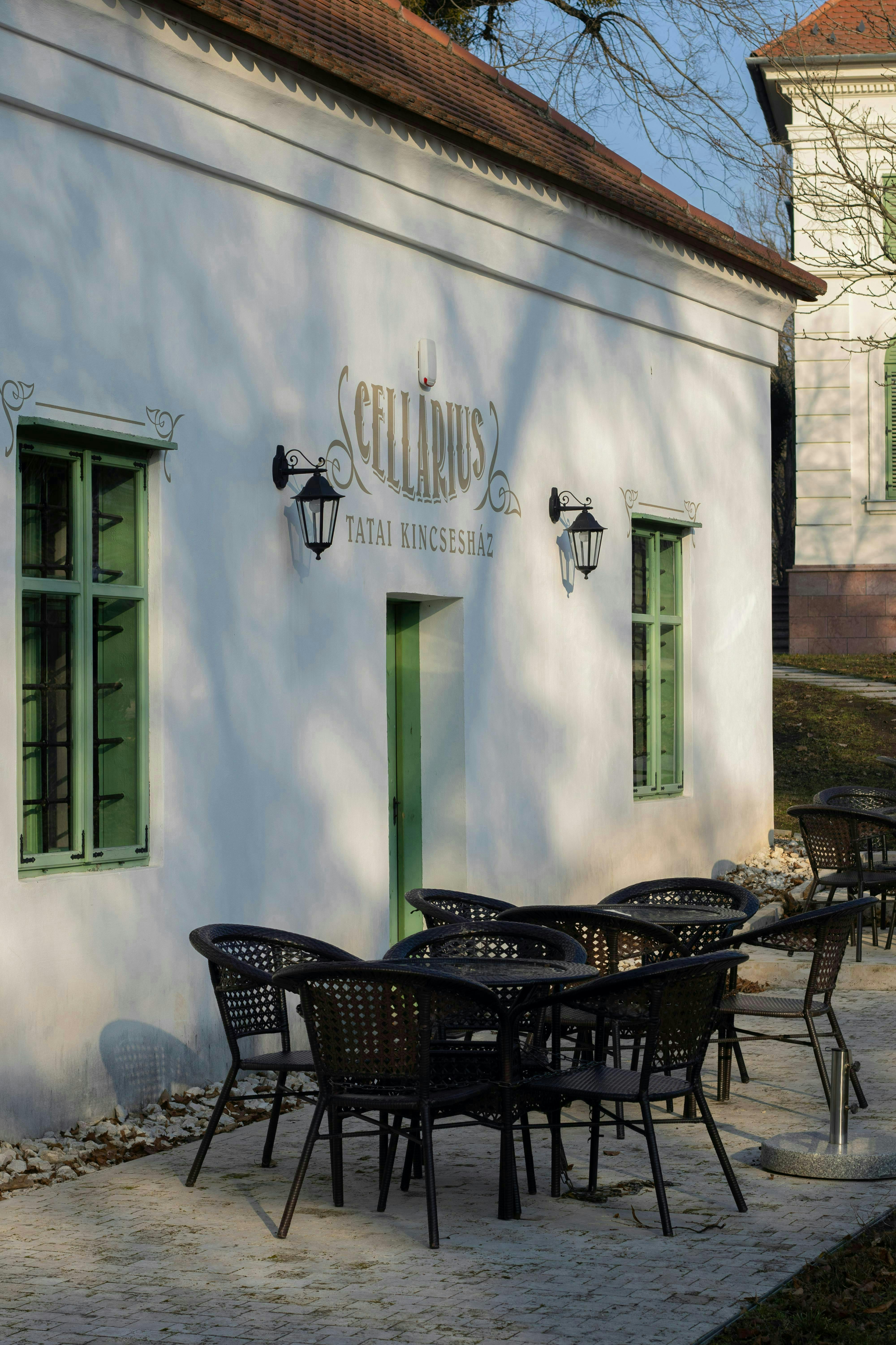 Empty cafe seating outside Cellarius vineyard building on a sunny day.