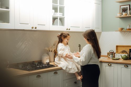 Free A heartwarming moment between a mother and daughter in a cozy kitchen setting. Stock Photo