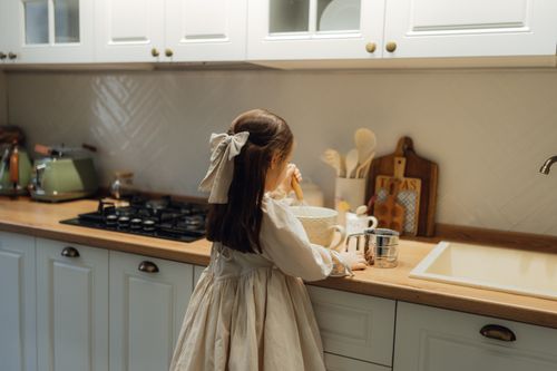 Free A young girl preparing a meal in a warm, modern kitchen setting. Stock Photo