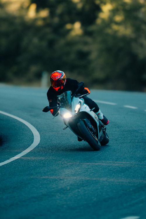 Free A motorcyclist with helmet riding swiftly on a curvy road during the day. Stock Photo