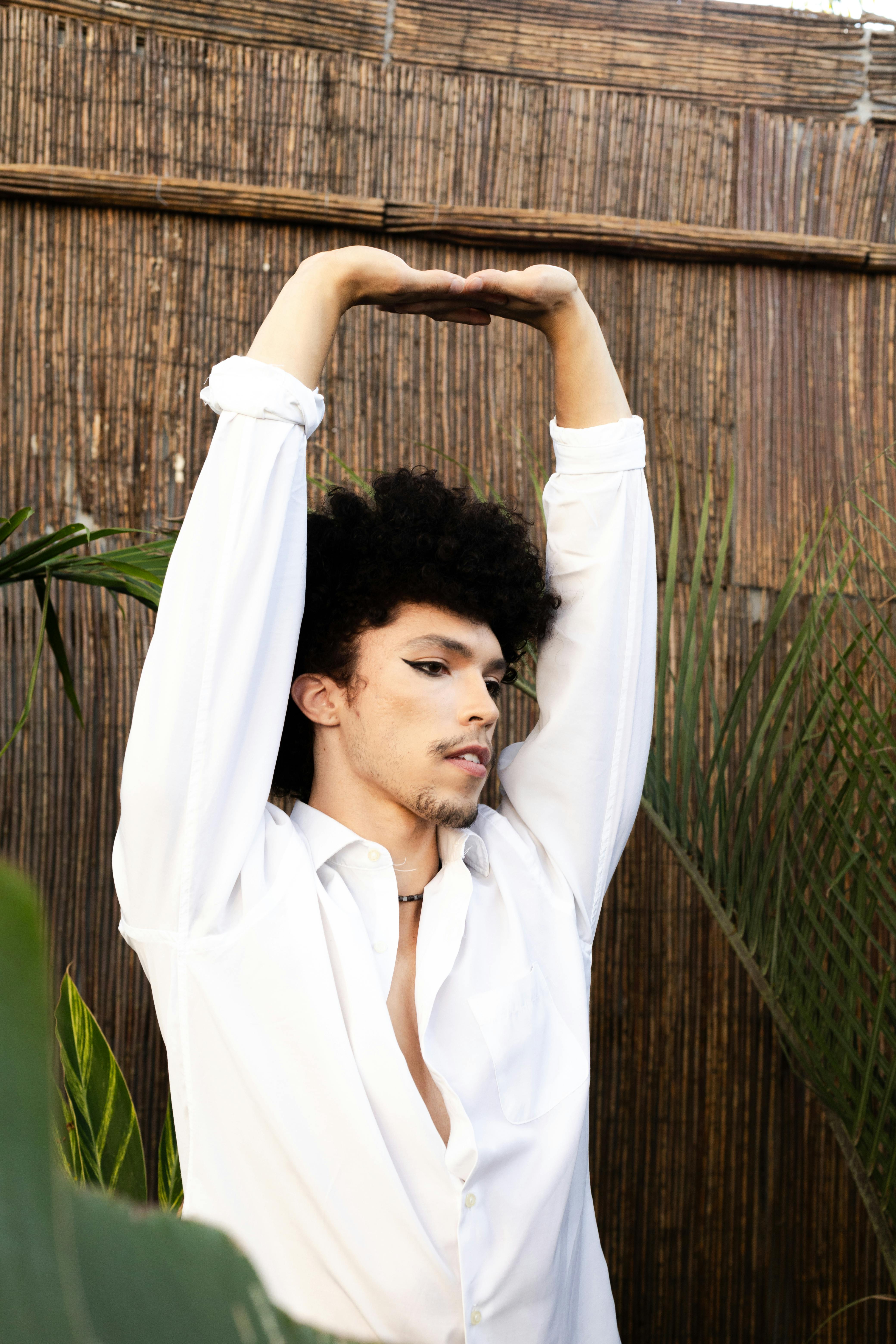Free Male portrait featuring a stylish man in a white shirt, set against a natural backdrop with bamboo and plants. Stock Photo