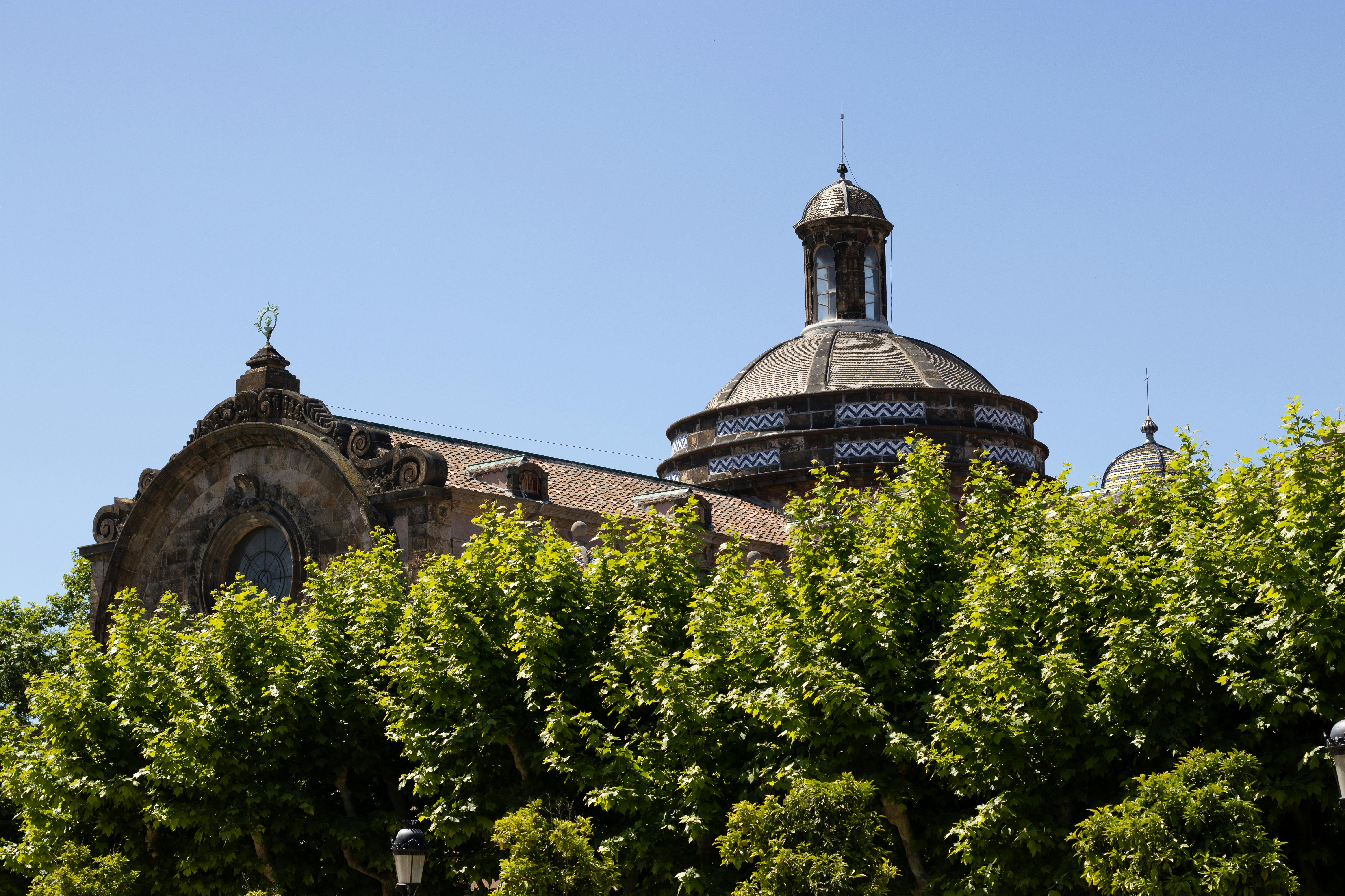 A view of classic Barcelona architecture with lush green trees under a clear blue sky.