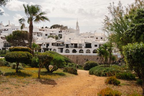 Free Charming white architecture in Ciutadella de Menorca with lush greenery and palm trees in foreground. Stock Photo