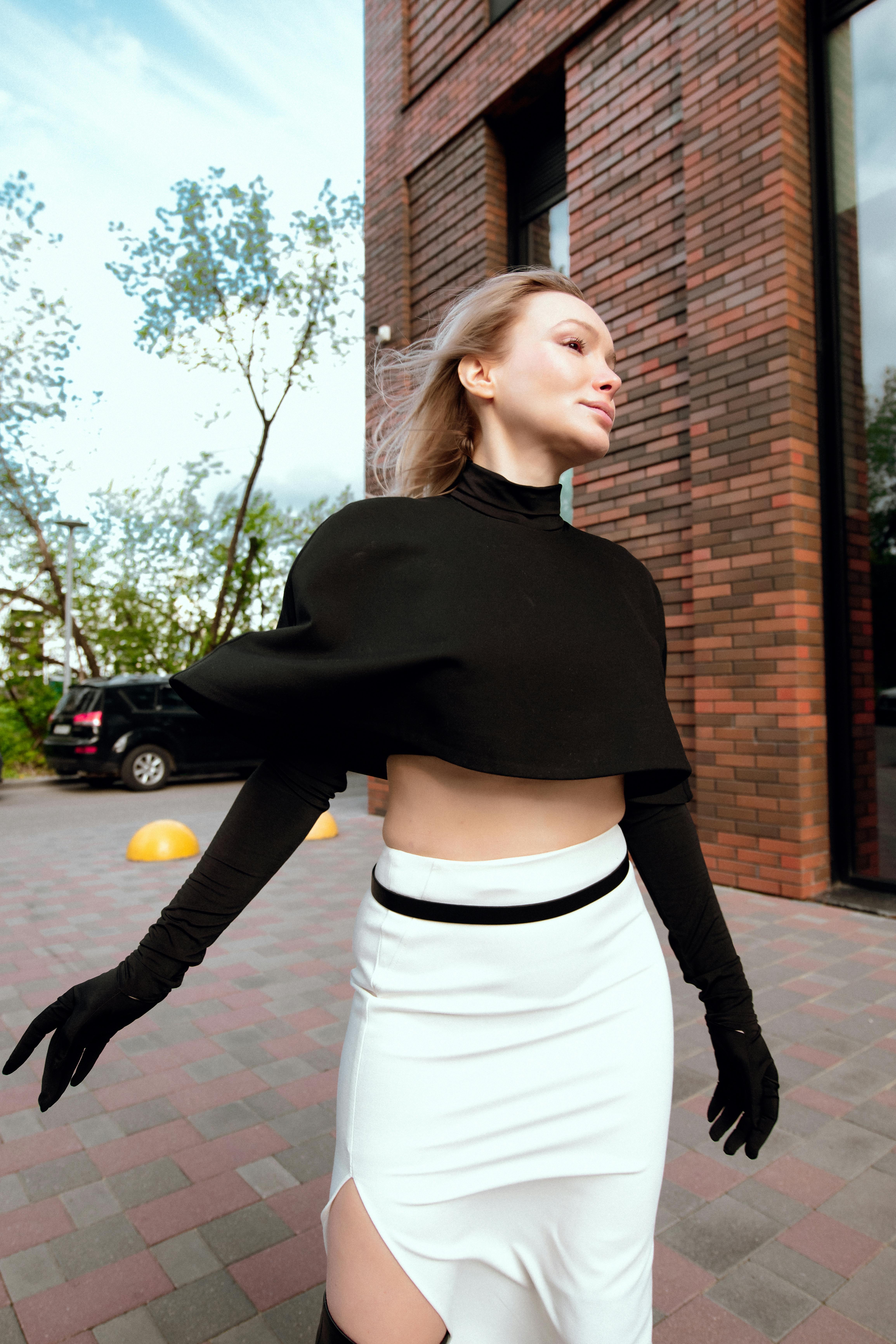 Free Fashionable woman in black and white outfit outside a brick building. Stock Photo
