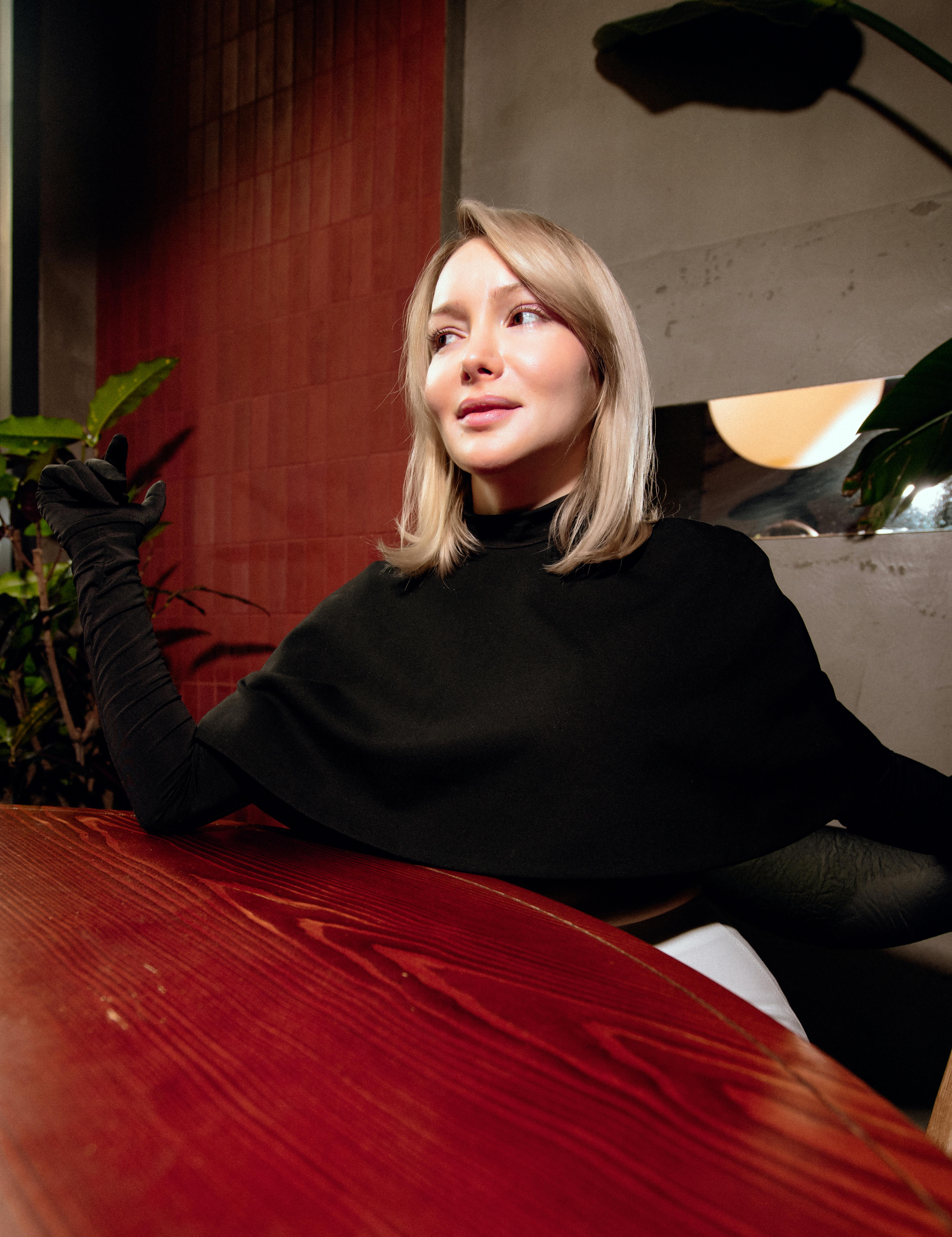 Gratis En moteriktig kvinne sitter innendørs på en kafé og utstråler eleganse. Arkivbilde