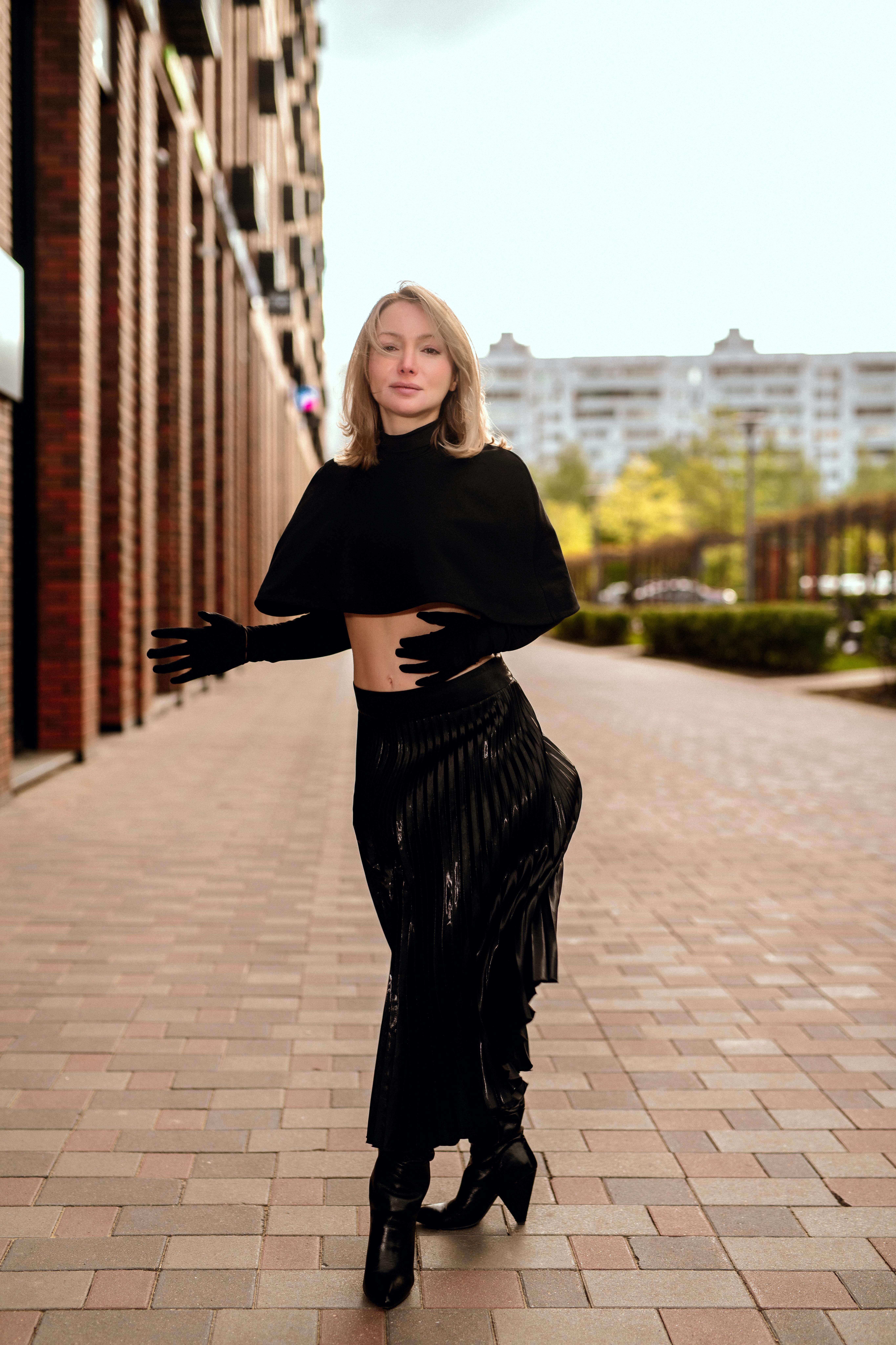 бесплатная Модная женщина стильно позирует в городской местности, демонстрируя современный наряд на фоне городского пейзажа. Стоковое фото