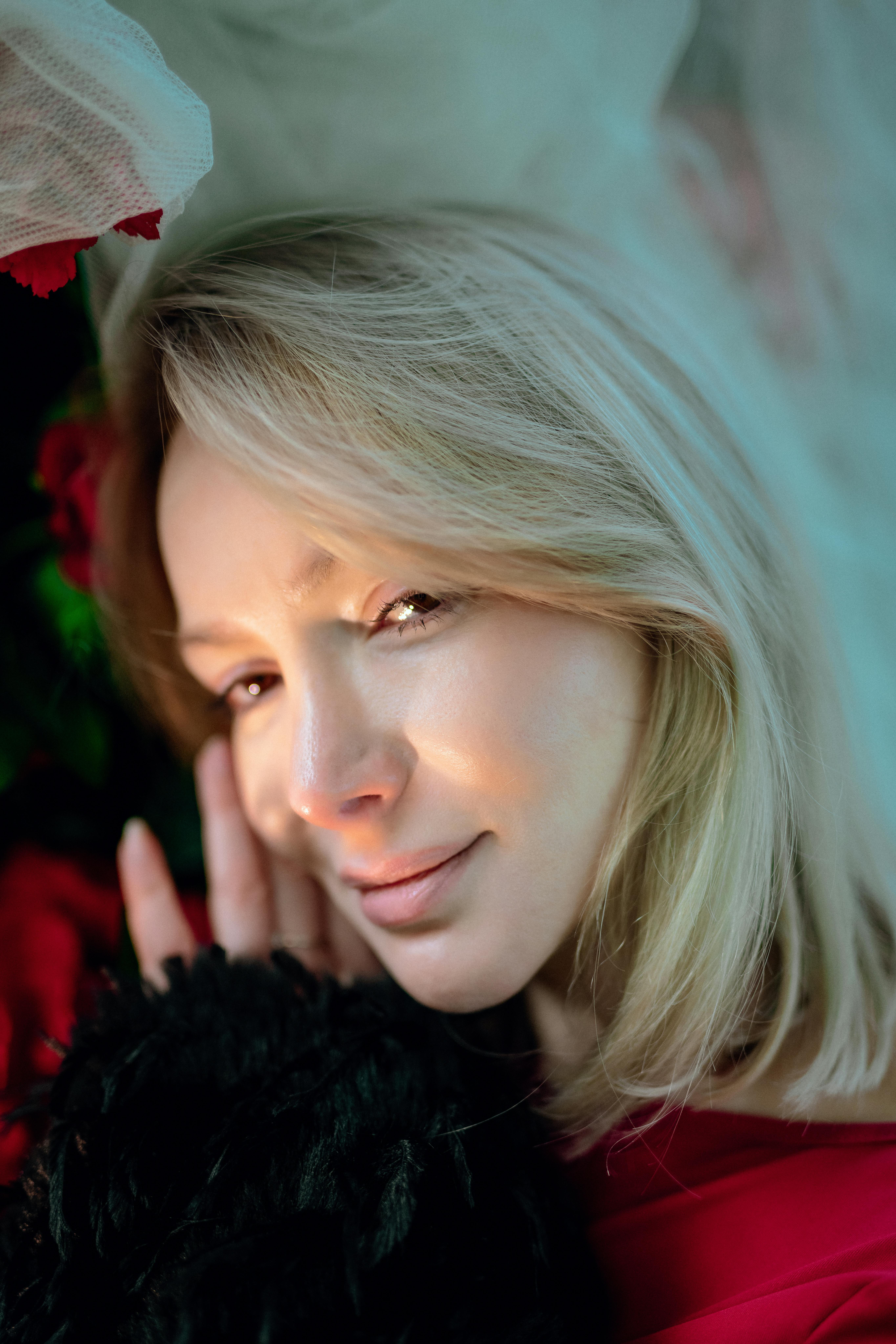 ingyenes Mosolygó nő közeli portréja beltérben, virágos elemekkel és lágy megvilágítással. Stockfotó