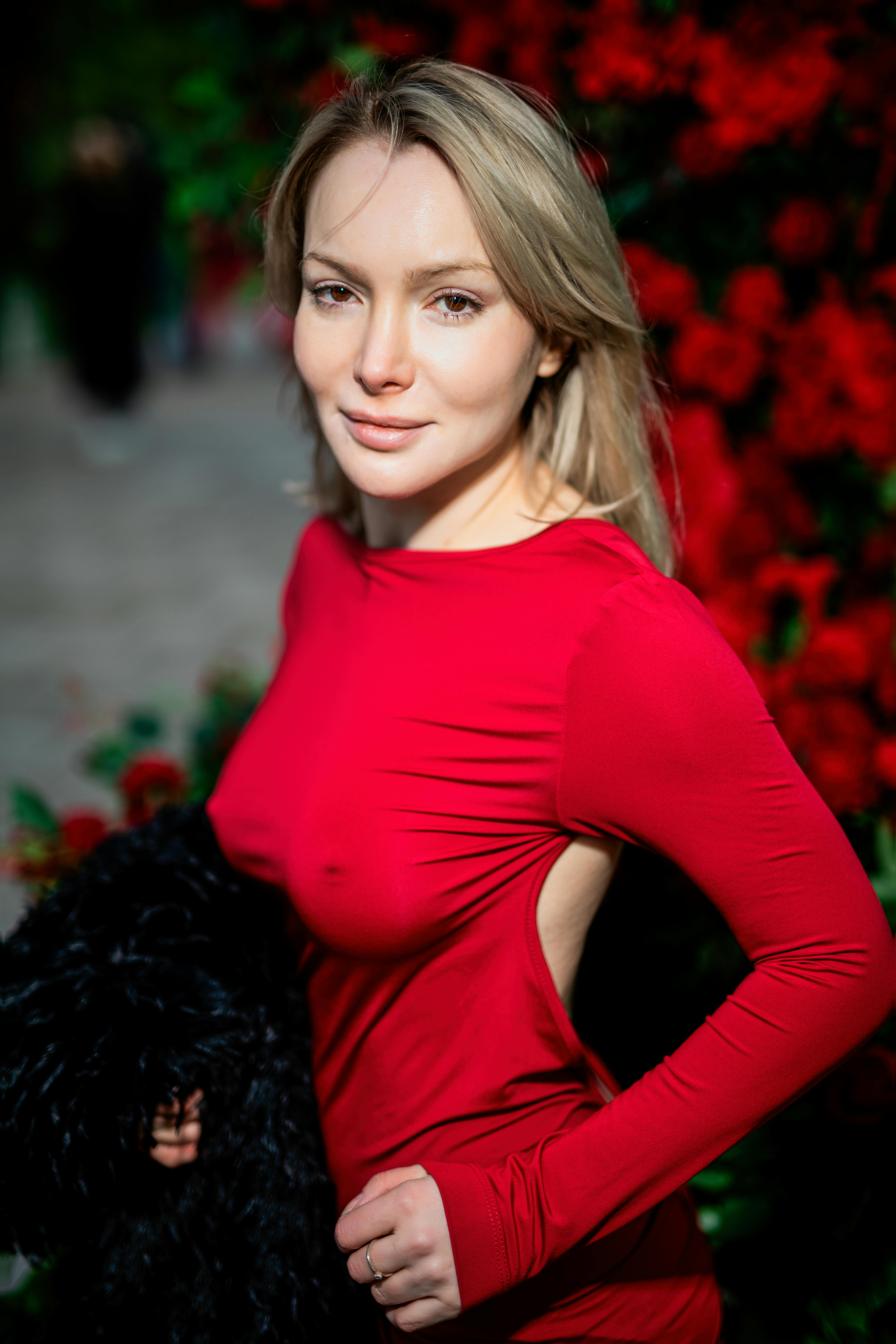 бесплатная Стильная женщина в ярком красном платье стоит на фоне ярких цветов. Стоковое фото