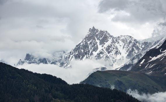 Snow-capped Aiguilles du Midi peaks surrounded by clouds in Chamonix, France. A breathtaking alpine view.