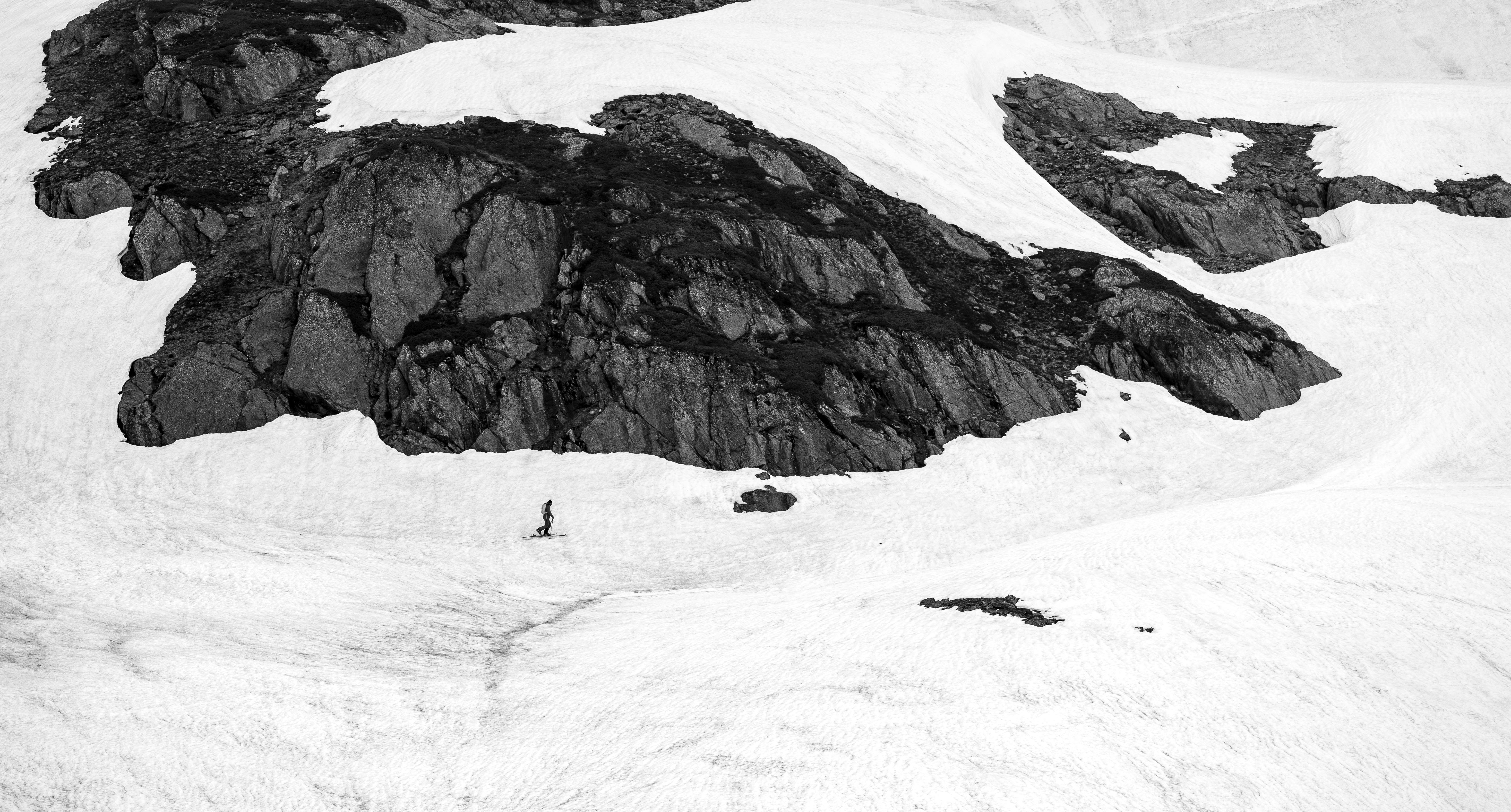 Black and white photo of a skier navigating snow-covered rocky terrain in the Alps.