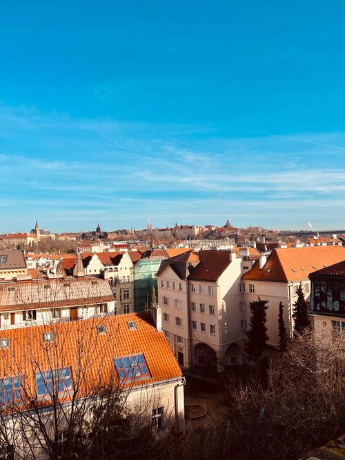 Free Charming aerial view of Prague's historic rooftops under a vivid blue sky, with beautiful architecture. Stock Photo