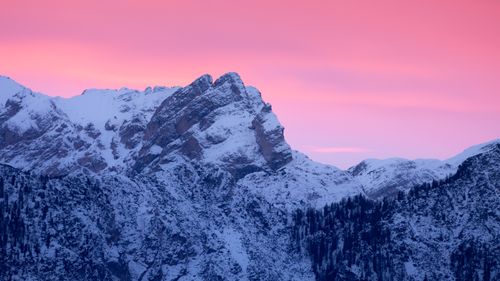 Free Capture of snow-covered mountain peaks with a vibrant pink sunset sky, exemplifying winter serenity. Stock Photo