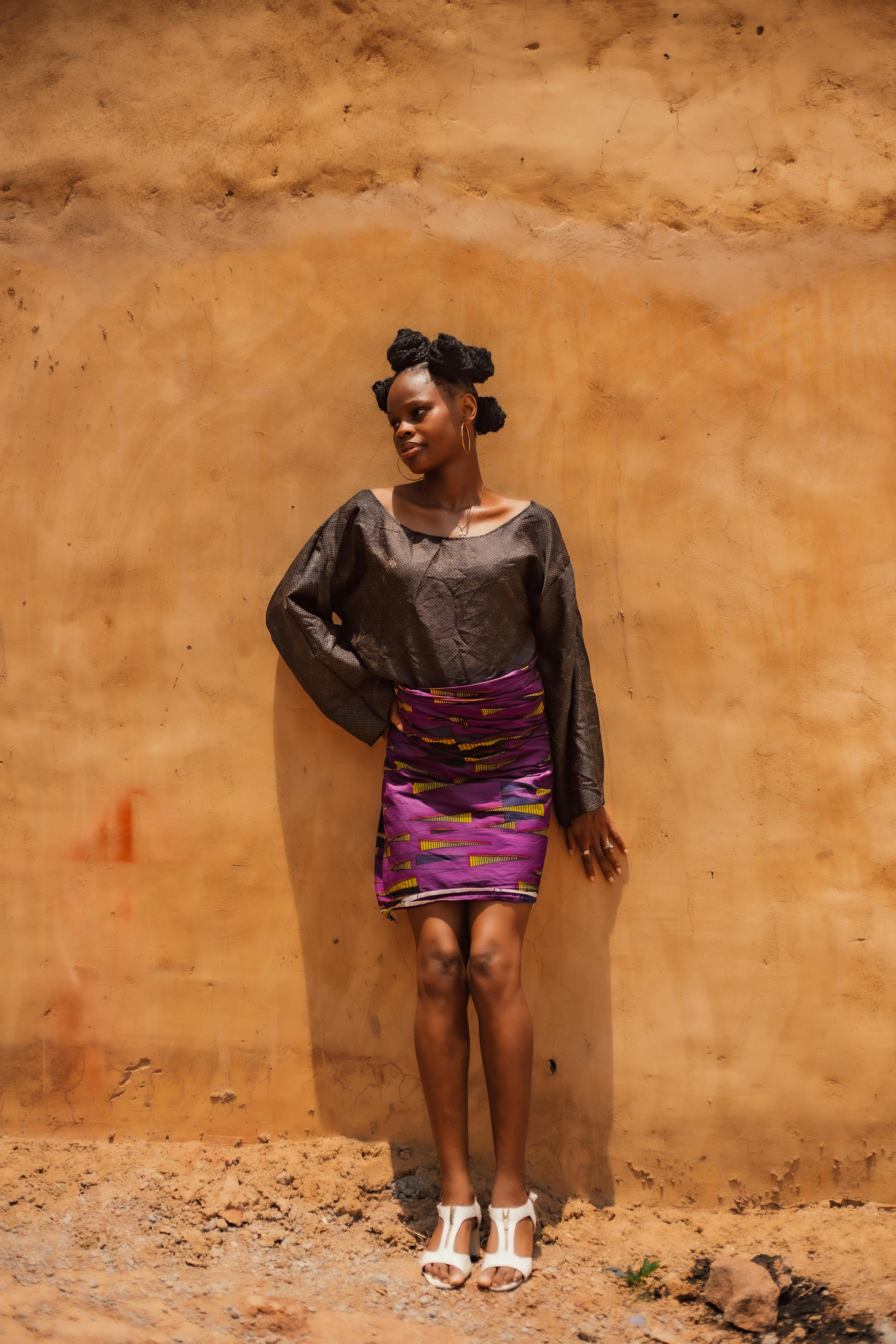 Fashionable young woman poses against a textured wall in vibrant attire