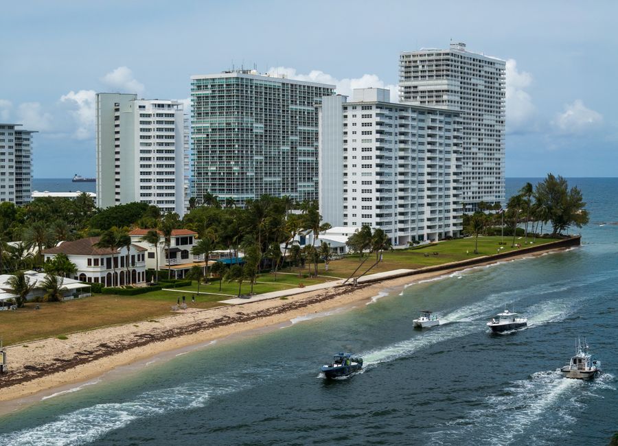 Aerial view of Fort Lauderdale high-rise buildings along the beach with boats on the water, exemplifying coastal city life.