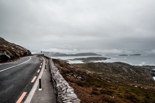 蜿蜒的道路沿着崎岖的海岸线延伸，在多云的天空下，可以看到壮观的海景