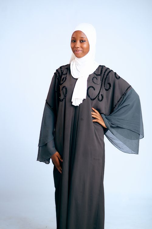 Free Portrait of a woman in a black embellished abaya and white hijab, posing confidently. Stock Photo